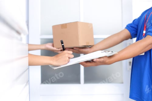 Preview: Close-up Of Deliveryman Holding Cardboard Box While Woman Hand Putting Signature on Clipboard.