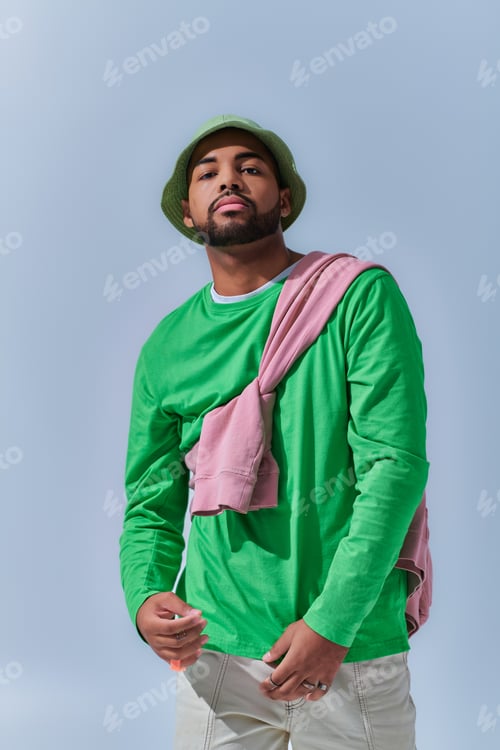 Preview: stylish young man in green panama with pink sweatshirt tied on his shoulders, fashion concept