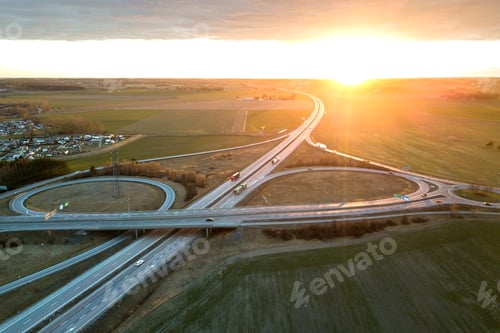 Preview: Aerial view of modern highway road intersection at dawn on raising sun background.