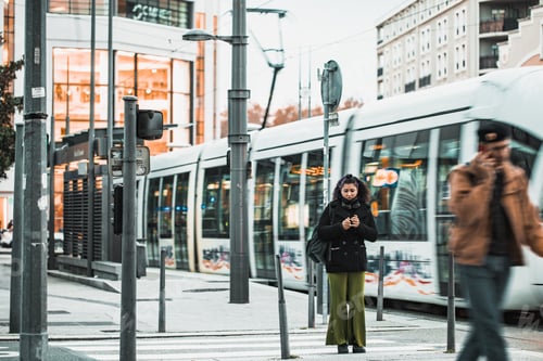 Preview: Urban scene of a woman standing in the street and a tramway behind her