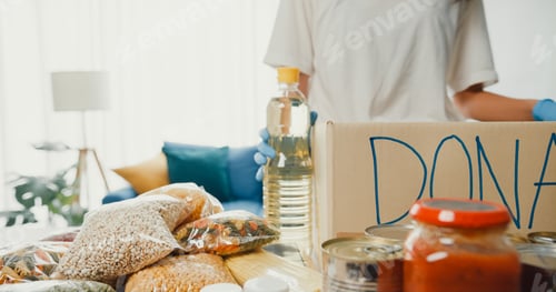 Preview: Girl volunteer wear gloves packing food and drinks donation into donations paper boxes.