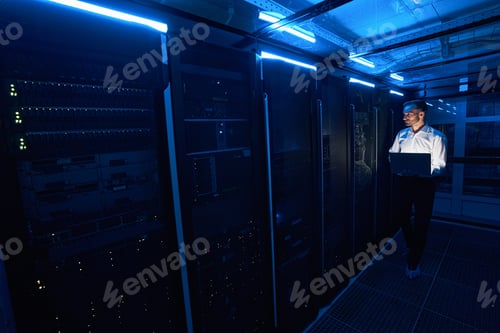 Preview: Male server technician walking with laptop in data center room