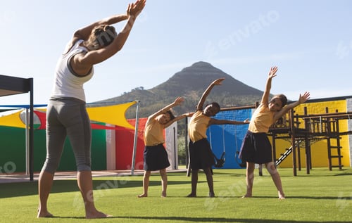 Preview: Trainer teaching yoga to students in school playground at schoolyard