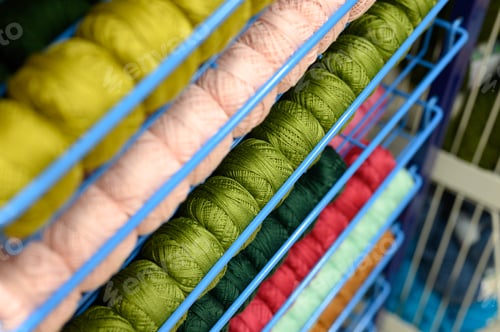 Preview: rows of balls of colorful cotton yarn threads for knitting pale pink and green colors on the shelves