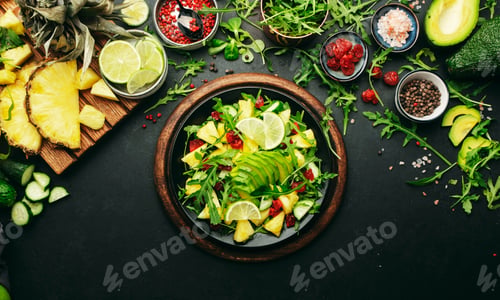 Preview: Vegan vegetarian salad with pineapple, arugula, avocado and dried cherry on black plate