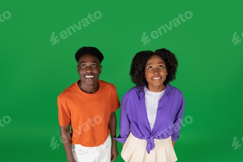 Preview: Happy shocked millennial african american couple in casual looking up, enjoy holiday