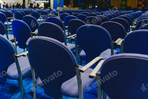 Preview: Many empty blue row chairs in a theater.