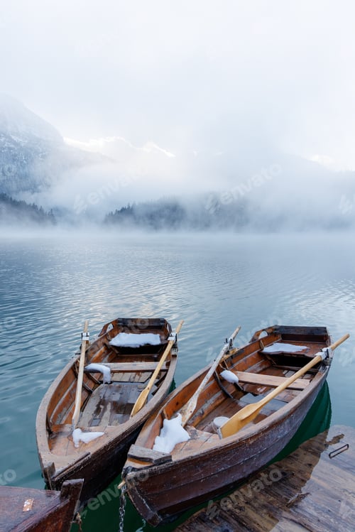 Preview: Wooden boats by the pier on a lake at sunset with mist rising over the water