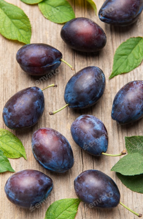 Preview: Ripe purple plums fallen on wooden table