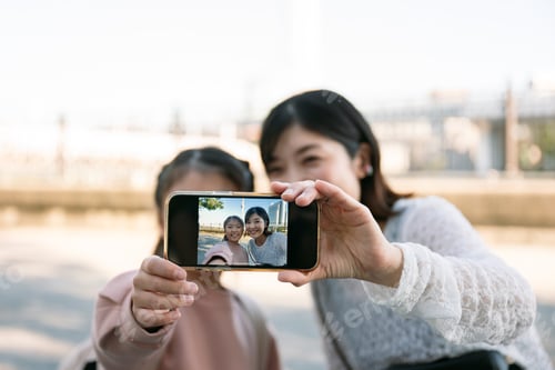 Preview: Mother and daughter taking selfie outdoors with smartphone in Tokyo Japan