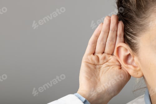 Preview: Close up of caucasian female doctor holding her ear on grey background