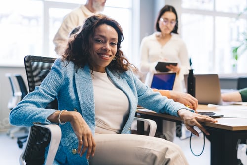 Preview: Cheerful black woman on chair in modern workspace
