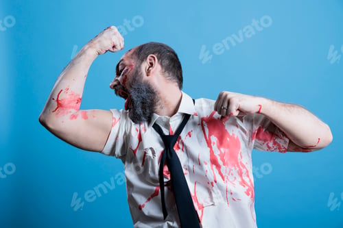 Preview: Strong actor dressed as thriller film zombie covered in blood flexing muscles