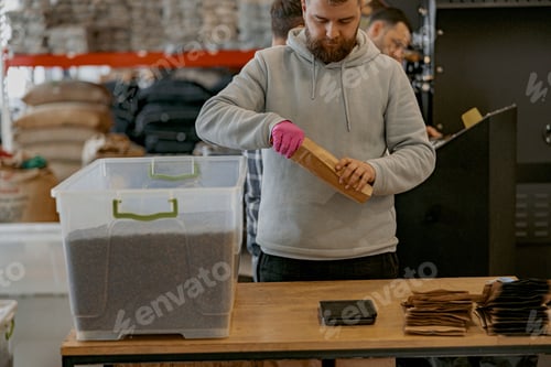 Preview: Male worker packs just roasted coffee beans into packages for sale