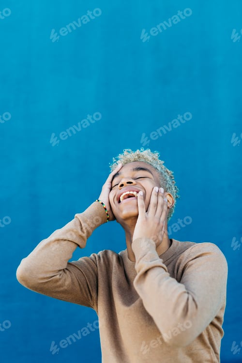Preview: Person Smiling and Touching Face Against Blue Background