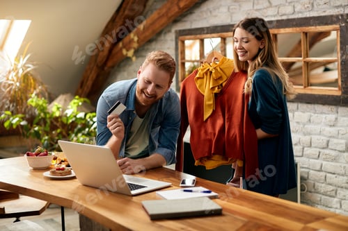 Preview: Happy couple using laptop and home shopping with credit card.