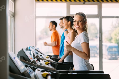 Preview: Healthy man and woman running on a treadmill in a gym