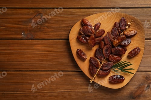 Preview: Branch with sweet dried dates and green leaf on wooden table, top view. Space for text