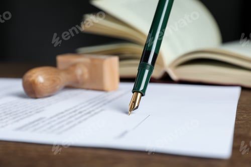 Preview: Signing notary document with fountain pen at wooden table against black background, closeup