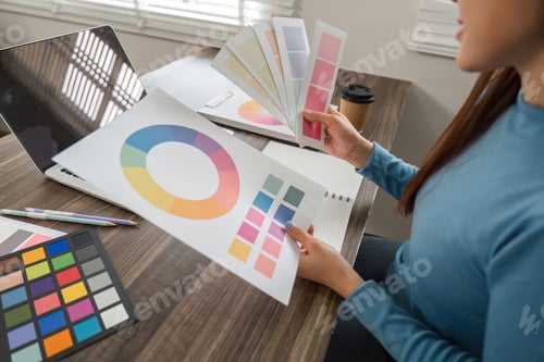 Preview: An artist analyzing color schemes and refining design elements at her desk.