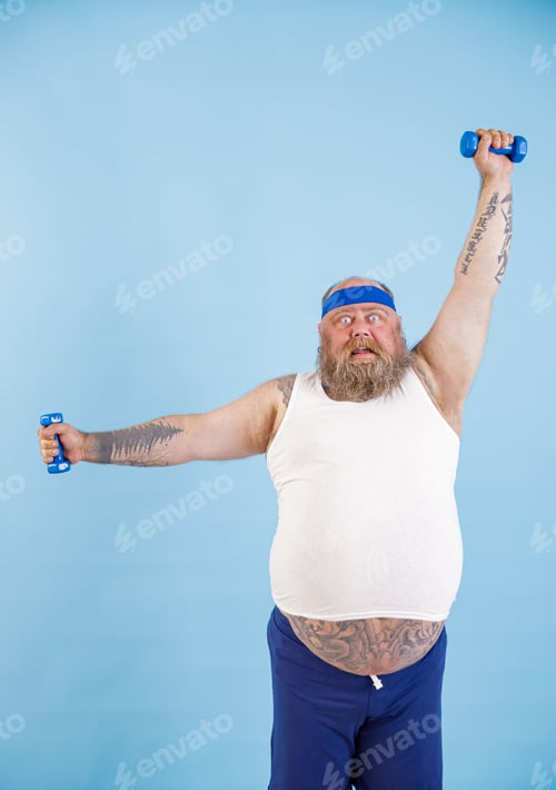Preview: Shocked obese man does exercises with dumbbells training hard in studio