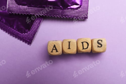 Preview: Condoms and word AIDS made with wooden cubes on violet background, flat lay. Safe sex