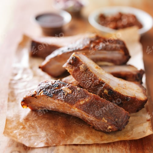 Preview: grilled barbecued ribs cut into pieces on wooden cutting board