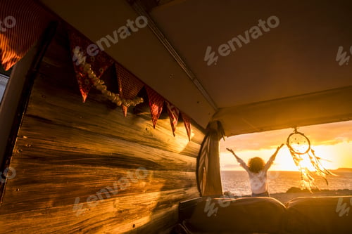 Preview: Rear view of woman with arms outstretched admiring scenic seascape during sunset