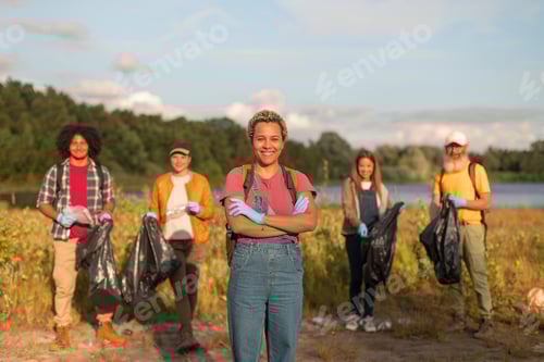 Preview: outdoors portrait of a smiling female volunteer cleaning the lake area nature park