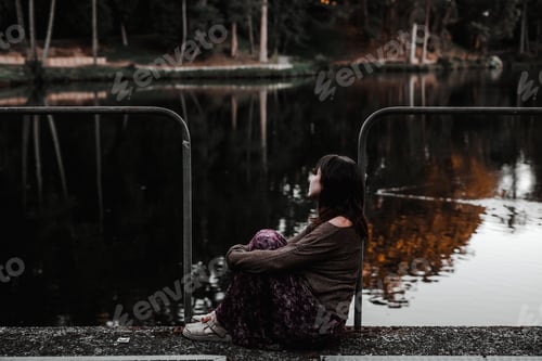 Preview: girl,young,woman sitting relaxed looking at the reflections of the river water