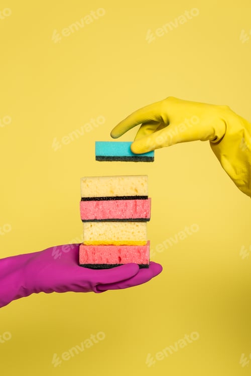 Preview: partial view of woman in rubber glove holding stack of sponges near man isolated on yellow