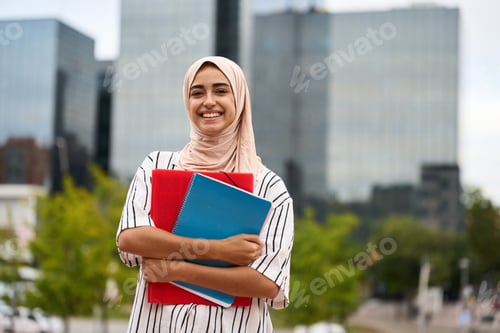 Preview: Muslim woman student holding books on campus