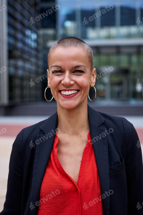 Preview: Shaven middle aged Caucasian business woman in suit poses standing outside office modern area.