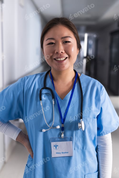 Preview: Portrait of happy asian female doctor in hospital corridor