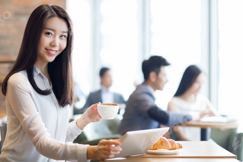 Preview: Young woman using digital tablet in café