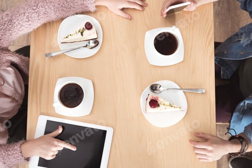 Preview: cropped image of children sitting at table with gadgets on surface at cafe
