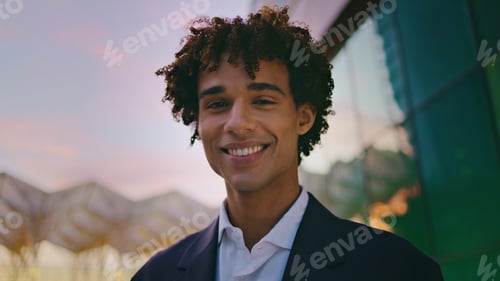 Preview: Smiling businessman posing sunset city portrait. Curly young man looking camera