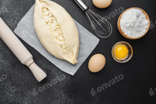 Preview: Raw khachapuri with cottage cheese and ingredients on black background