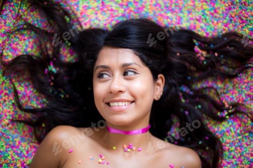 Preview: Beautiful sexy Mexican woman smiling and lying on colourful bright background
