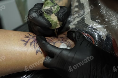 Preview: Tattoo Artist Carefully Inking Tree Design on Arm