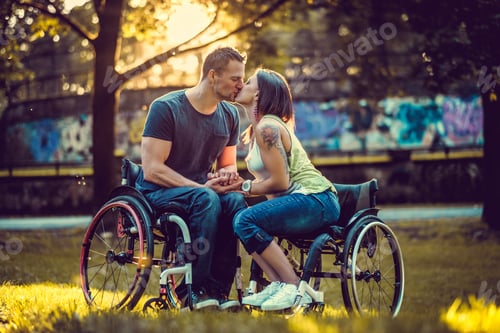 Preview: Handicapped young couple on two wheelchairs kissing .