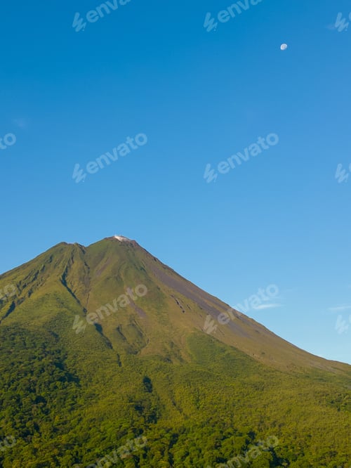 Preview: Beautiful landscape of Arenal Volcano in Costa Rica with a clear blue sky and the moon visible