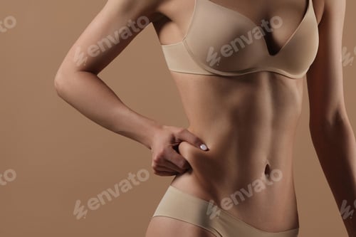 Preview: Thin young woman in underwear on beige background