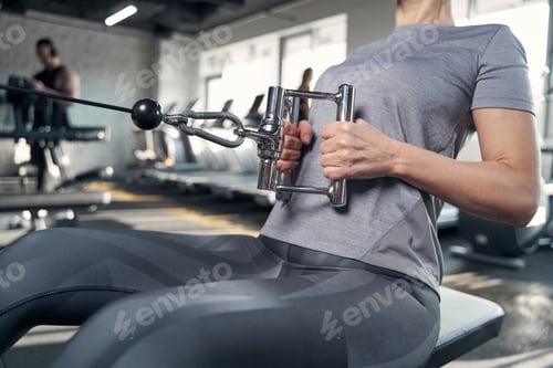 Preview: Sporty woman using gym workout equipment in fitness center