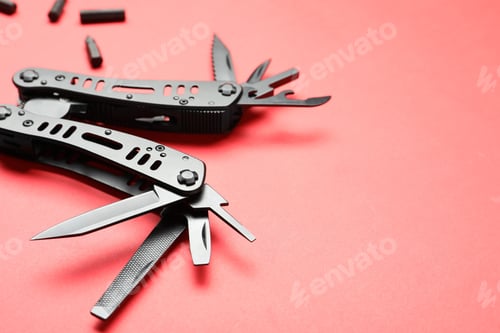Preview: Compact portable black multitool and details on red background, closeup. Space for text