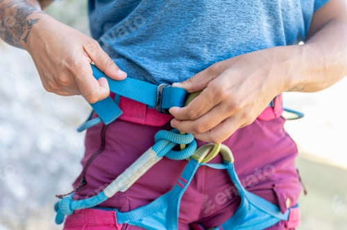 Preview: Climber tightening harness getting ready for climbing mountain