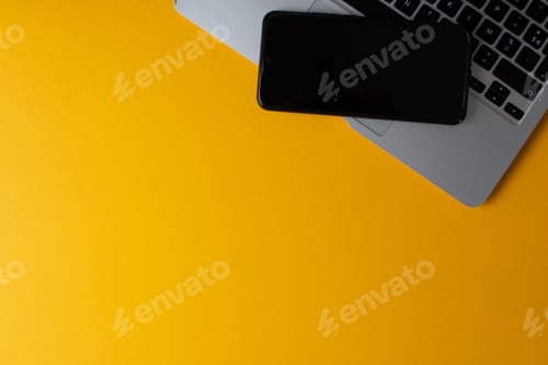 Preview: Top view of a laptop and cellphone on a yellow background
