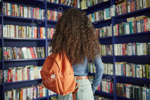 Preview: Young Adult Black Woman Standing in Library Browsing Bookshelves