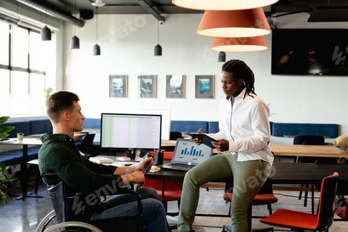 Preview: African american young businessman discussing with caucasian colleague sitting in wheelchair