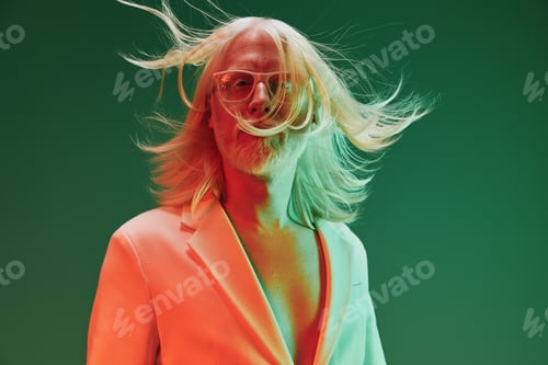 Preview: Stylish man with long hair in a vibrant green and orange background, wearing glasses and a